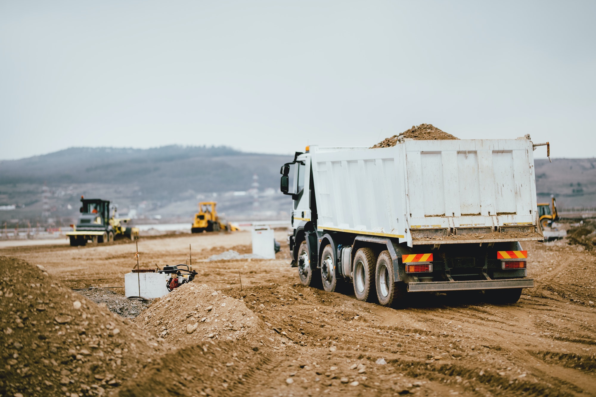 Industrial dumper trucks working on highway construction site,